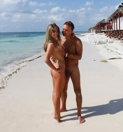 Обнаженные люди наслаждаются солнцем на песчаном берегу