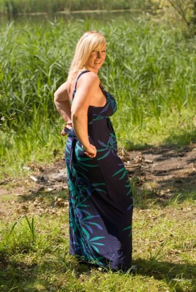 Зрелая женщина наслаждается у реки: откровенные моменты на природе