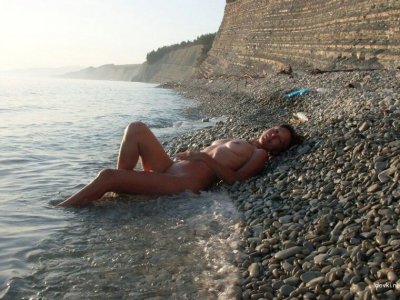 Обнаженная девушка на галечном берегу
