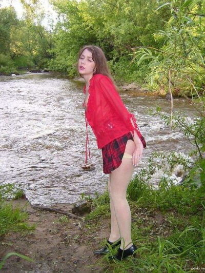 Обнаженная красавица позирует у живописной реки в лучах солнца