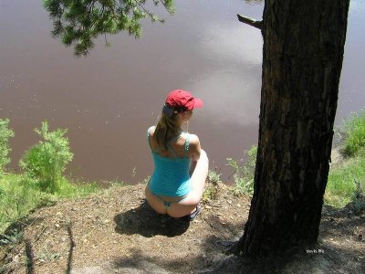 Развратная блондинка без верхней одежды среди деревьев