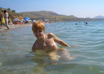 Сексуальная рыжеволосая красотка наслаждается отдыхом на пляже