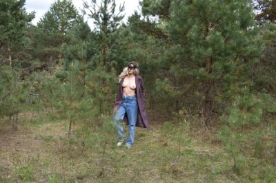 Дама снимает одежду в лесу и позирует перед камерой