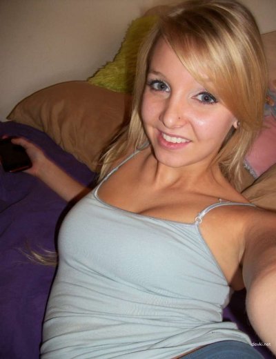 Очаровательная блондинка сбрасывает одежду на уютной кровати